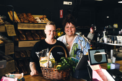 Kym and Sarah instore at Good Things Grocer Tarragindi Brisbane. Freshly baked bread in the background and a basket of fresh produce and gourmet food is in the foreground.